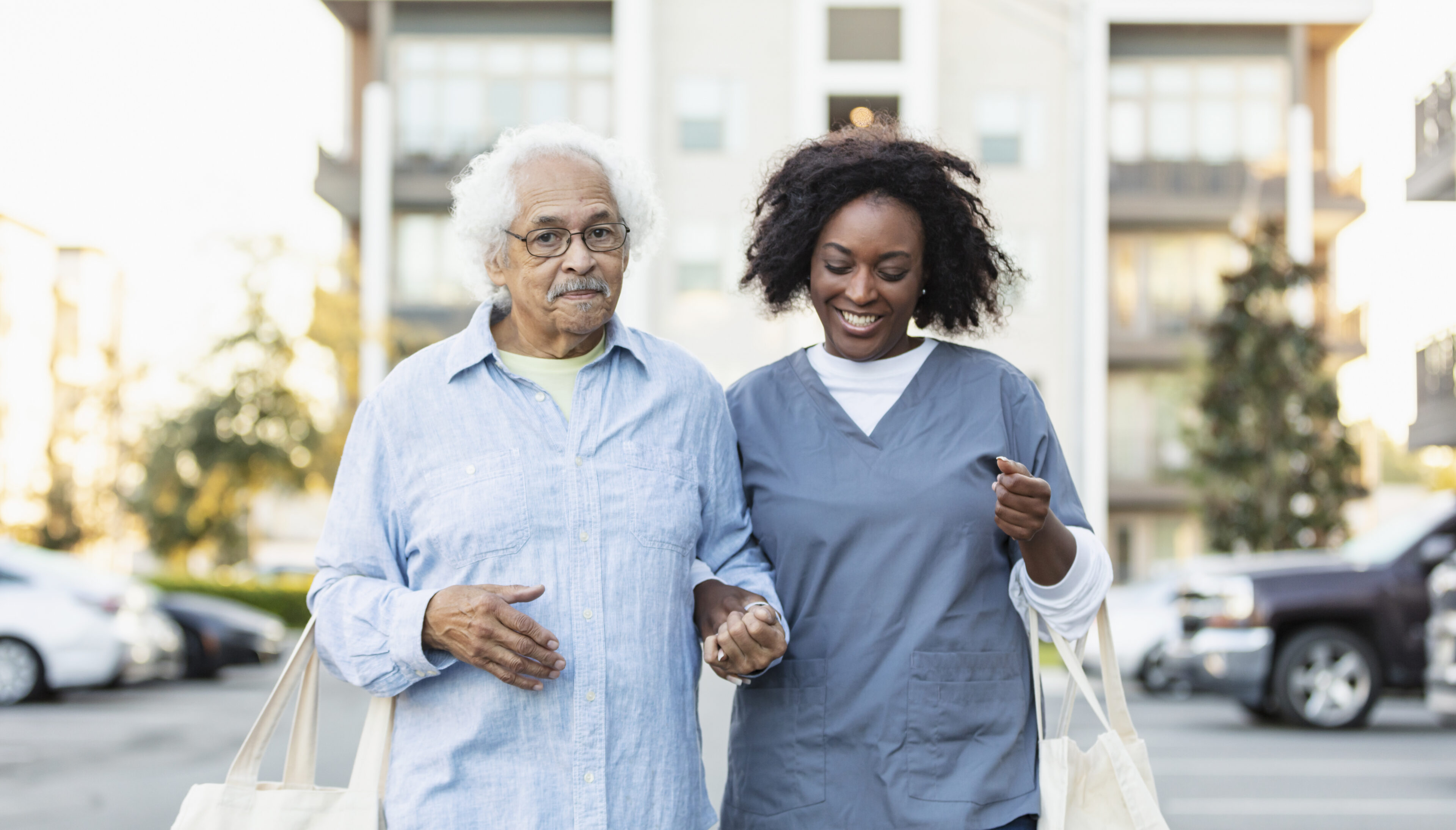 Senior man with caregiver talking, carry reusable bags