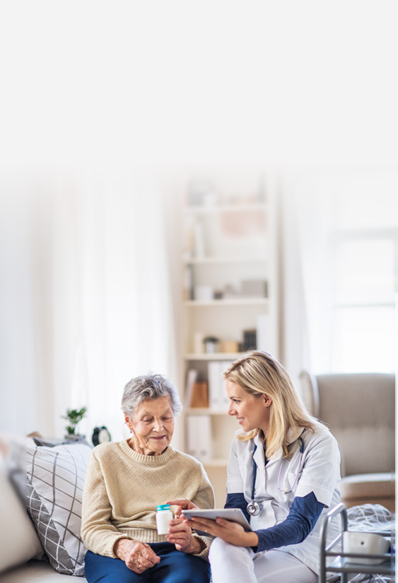nurse sitting next to her patient and handing her patient a bottle of medication