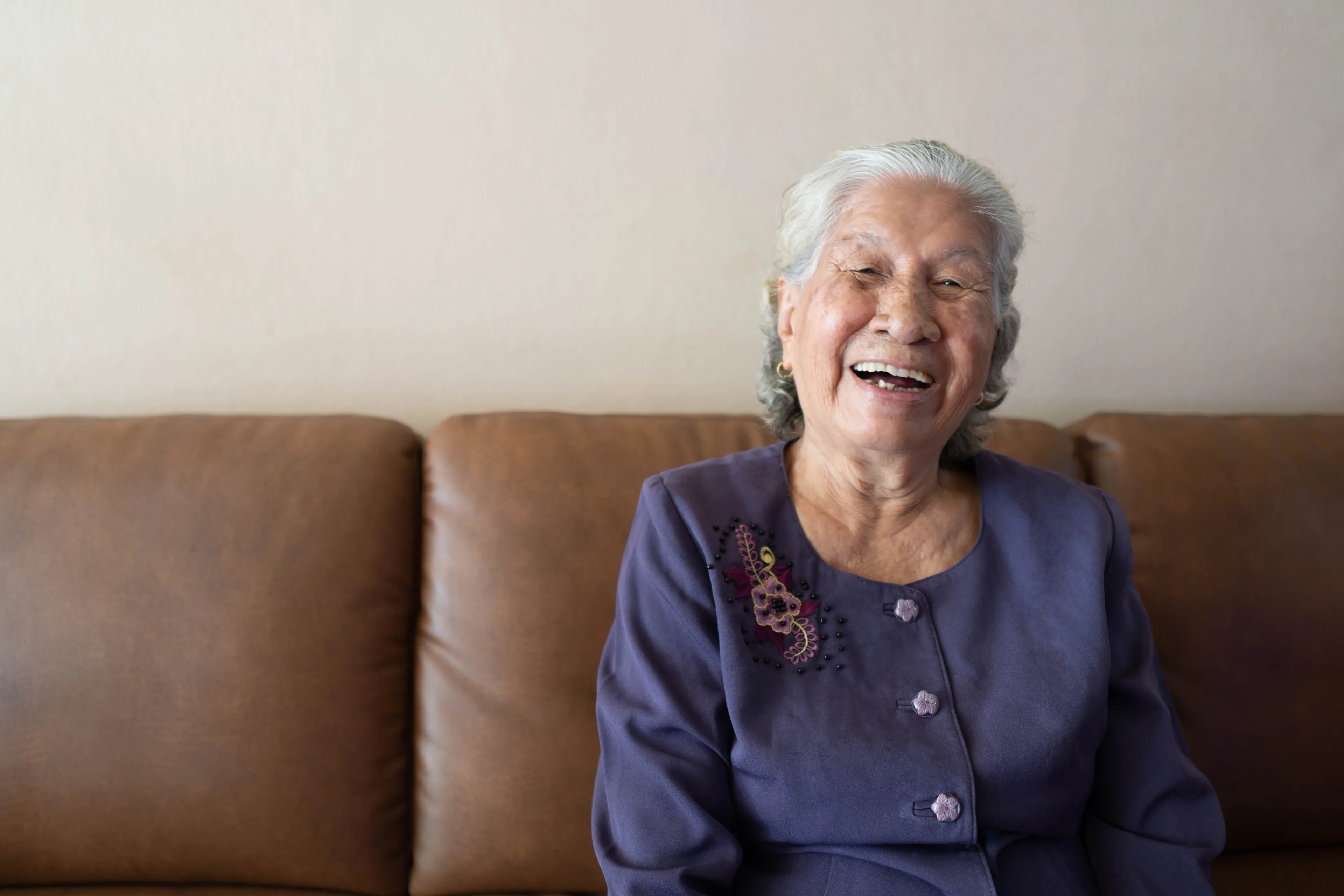 An elderly woman sitting on a couch, smiling